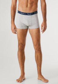 Graue Baumwoll-Boxershorts mit einem marineblauen elastischen Bund, der weißen Logo-Text trägt. Das Design hat eine enge Passform und eine glatte Textur.
