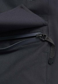 Tela negra con un zipper impermeable parcialmente abierto y un tirador tejido unido al deslizador del zipper.