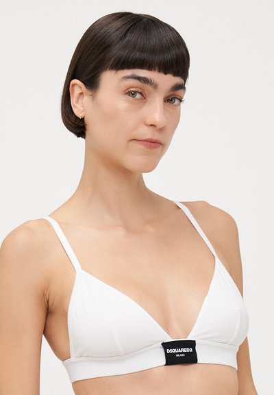 Bralette bianco triangolare con spalline sottili e un'etichetta logo al centro. Tessuto liscio con cuciture minime e un design semplice.