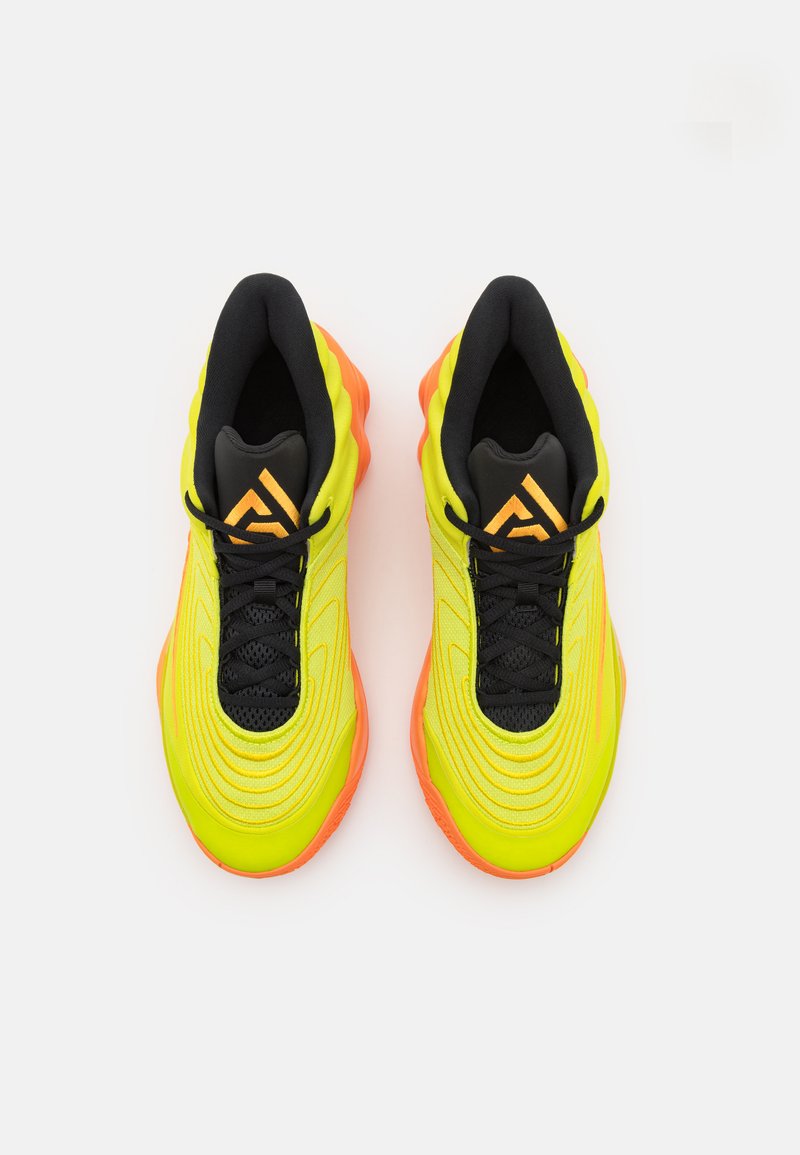 Sneakers atletiche giallo neon con dettagli neri, presentano un upper testurizzato, un puntale liscio e suole in gomma arancione. Il design include un sistema di allacciatura centrale.