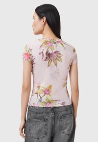 Blomster kortærmet top i lyserød stof, med et tropisk blad- og blomstermønster, i en tætsiddende design og rund halsudskæring.