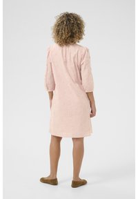 Pink dress with three-quarter sleeves featuring floral embroidery, loose fit, and a straight hem. Paired with brown flat shoes.