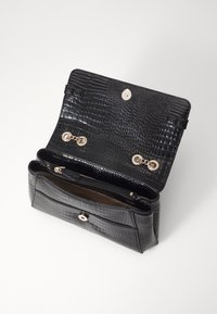 Schwarze krokodilgeprägte Lederhandtasche mit goldener Hardware, ausgestattet mit einem Klappenverschluss und einer Innentasche mit Reißverschluss, die eine glatte Textur aufweist.
