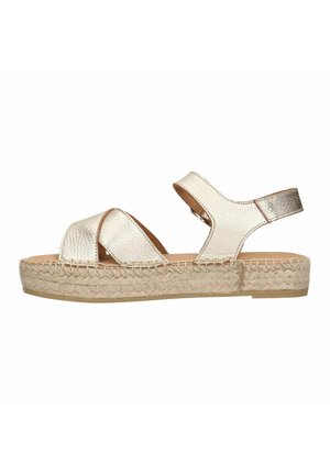 Gouden metallic sandalen met twee brede banden, een achterband en een geweven espadrille zool. Het ontwerp heeft een platte hak en een gladde textuur.