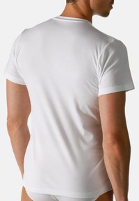 T-shirt bianco in cotone con maniche corte, scollatura rotonda e superficie liscia, vista da dietro. Nessun motivo o dettaglio visibile.