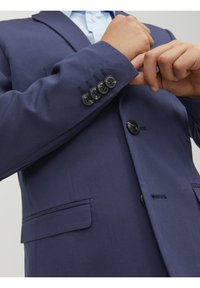 Granatowa marynarka w stylu garniturowym z teksturowanym wykończeniem, z zamknięciem na jeden guzik i czterema czarnymi guzikami na mankietach. Posiada gładki materiał i dopasowany krój.