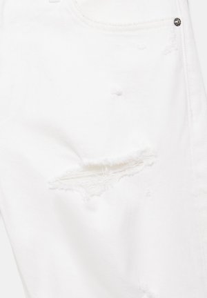 Belo jeansa blago z obrabljeno trganino nad stegno, z raztrganimi robovi in vidnim šivom blizu kovinskega zakovicnega gumba.