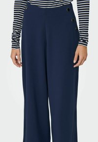 Navy wide-leg trousers made from a smooth fabric, featuring three decorative gold-tone buttons on the left side and a high waist design.