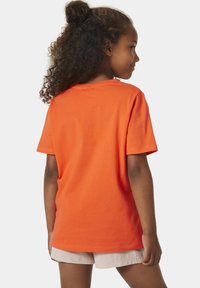 Camiseta de algodón naranja con mangas cortas y cuello redondo; textura suave y ajuste relajado, presentada desde la parte de atrás.