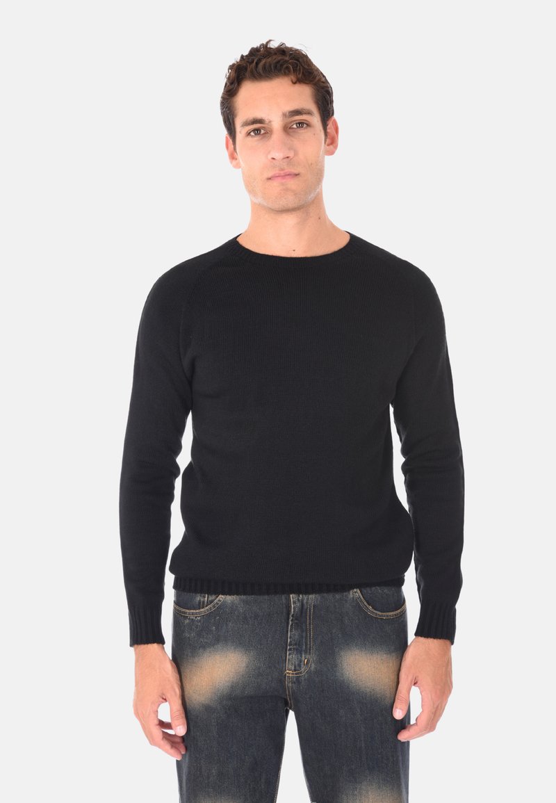 Maglione nero lavorato a maglia con collo rotondo, polsini e orlo a costine. Abbinato a jeans blu sbiaditi, che mettono in mostra un look casual e testurizzato.
