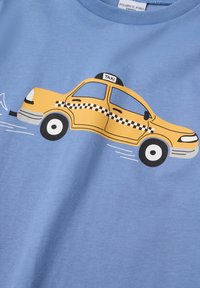 Gul taxa illustration med ternet stripe og "TAXI" skilt på blå stofbaggrund.