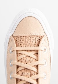 Sneaker beige chiaro con upper intrecciato testurizzato, puntale in tela, suola in gomma bianca e lacci piatti infilati in occhielli metallici.