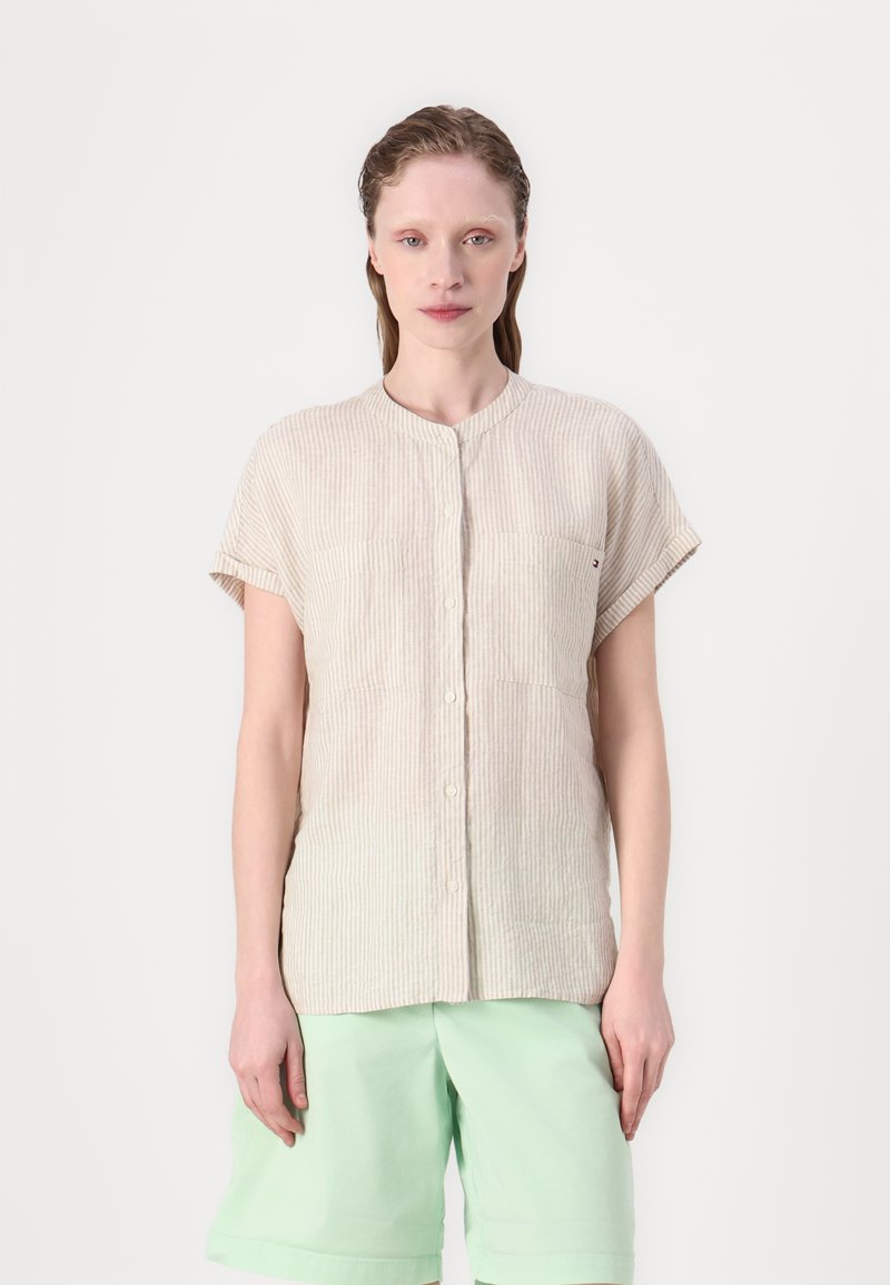 Camicia button-up a maniche corte a righe beige con colletto rotondo e due tasche sul petto, abbinata a pantaloni corti verde menta.