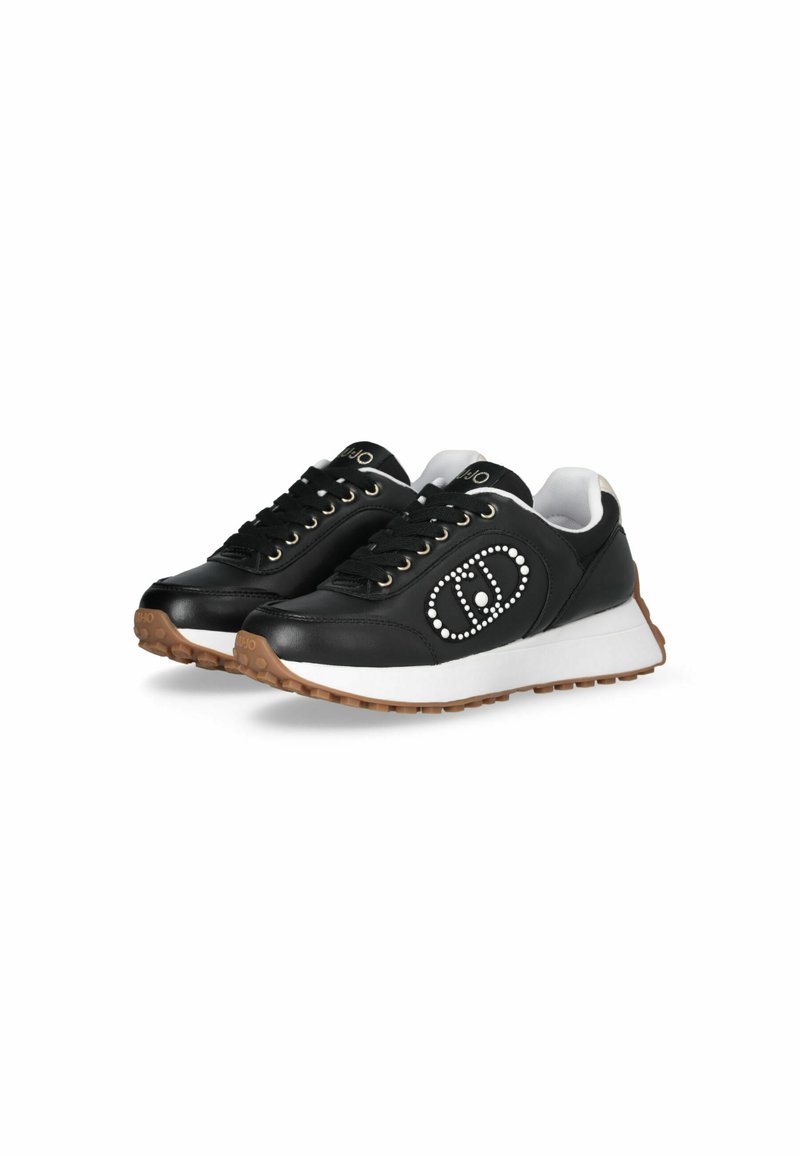 Baskets en cuir noir avec une semelle blanche, présentant des œillets dorés, un logo proéminent entouré de clous, et une semelle en caoutchouc texturée.