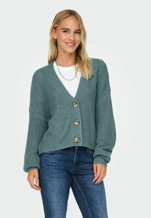 Cardigan en tricot bleu-vert avec un col en V, des manches longues et quatre grands boutons sur le devant. Tissu texturé et design court.