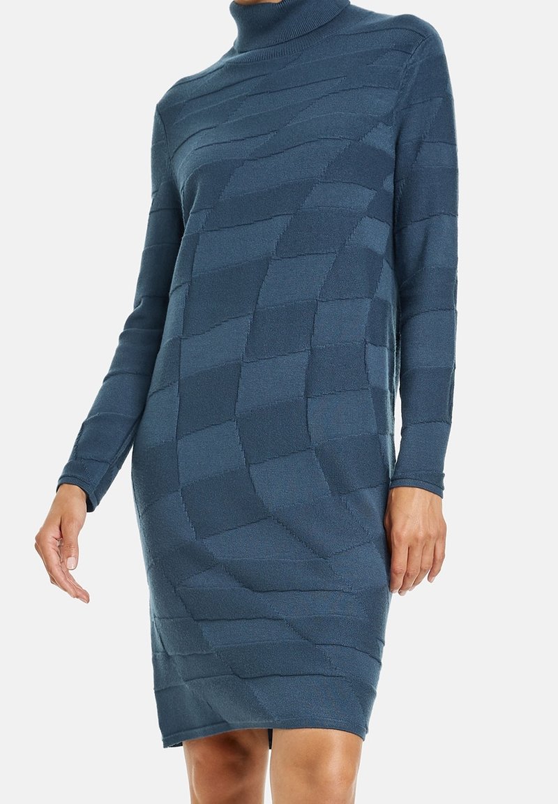 Robe col roulé d'un bleu profond, arborant un motif texturé de rayures horizontales et verticales, avec des manches longues et une silhouette ajustée.