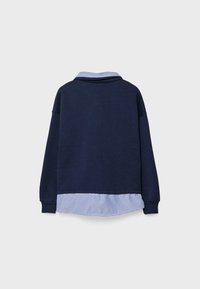 Marinblå sweatshirt med ett blått och vitt randigt bottenlager och krage. Har långa ärmar och en avslappnad passform, med ribbade manschetter.