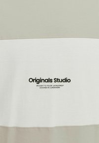 Gray and white striped T-shirt made of soft cotton. Features a logo print, contrasting stitching, and a rounded neckline.