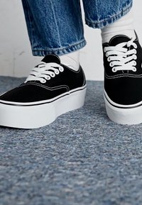 Black canvas sneakers with white laces and contrasting white sole, featuring a classic design and subtle stitching details.
