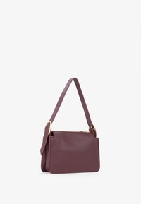 Borsa a mano in pelle bordeaux con forma rettangolare, tracolla rimovibile e zip dorata. Texture liscia con hardware minimale.