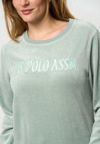 Ljusgrön långärmad sweatshirt med en mjuk textur. Har broderad "U.S. POLO ASSN." i en kontrasterande ljus nyans på framsidan.