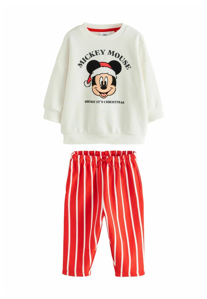 Fehér pulóver, amelyen egy nagy, nyomtatott Mickey Mouse látható, amint Mikulás sapkát visel, piros csíkos nadrággal párosítva, amely rugalmas derékpánttal rendelkezik.