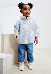 Cozy blue and light yellow fleece pullover with a half-zip design, paired with loose denim jeans and white sneakers. Simple and comfy fit.