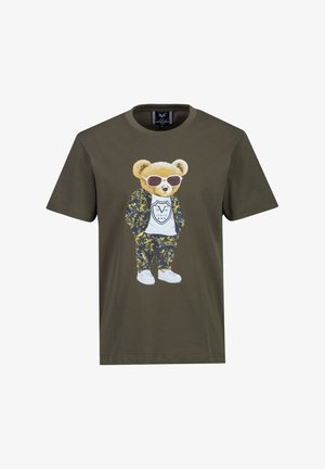 T-shirt vert olive avec un ours en peluche portant des lunettes de soleil, une veste et un pantalon à motifs, des baskets blanches, et un T-shirt blanc avec le logo "1969 ITALIA".