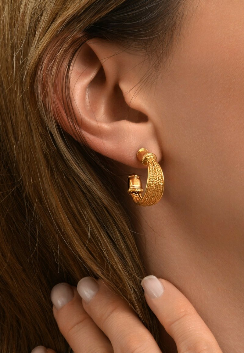 Boucle d'oreille en or avec un design texturé et une perle ronde proéminente. La boucle d'oreille a une finition lisse et met en valeur des détails complexes.