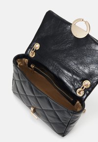 Čierna prešívaná kožená kabelka so zlatým kovovým zapínaním, vnútorným zipsovým vreckom a hladkou podšívkou.