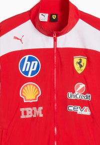 Veste Puma Ferrari rouge et blanche avec les logos de HP, Shell, IBM, UniCredit et CEVA sur le devant.