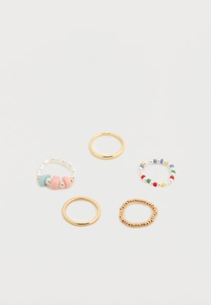 Conjunto de cinco anillos: uno con cuentas y perlas en tonos pastel, tres bandas de metal dorado con diseños variados y un anillo con cuentas de colores.