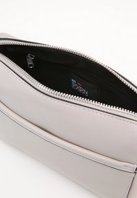 Clutch bag in pelle grigia chiara con zip silver e foderatura interna nera, dotata di una piccola tasca con zip e etichetta del marchio.