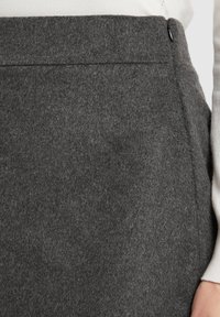 Grauer, glatter Rock aus einem weichen und warmen Material, mit einem versteckten Reißverschluss und klarer Nahtgestaltung.