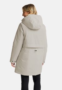Parka grigio chiaro con cappuccio, caratterizzata da una vestibilità rilassata, vita sintonizzata e polsini con bottoni. Texture liscia e dettagli di design minimali.