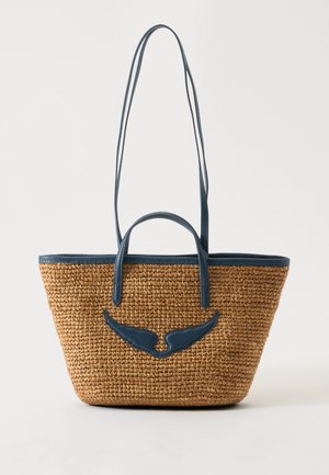 Woven straw tote bag with navy blue leather trim, two short handles, long shoulder straps, and wing-shaped leather detail on front.
