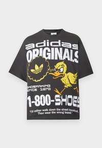 Μαύρο t-shirt Adidas Originals με λευκό κείμενο, γραφικό ενός κίτρινου θυμωμένου πάπιας και την φράση "1-800-SHOES" στο μπροστινό μέρος.
