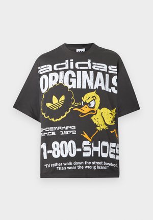 Μαύρο t-shirt Adidas Originals με λευκό κείμενο, γραφικό ενός κίτρινου θυμωμένου πάπιας και την φράση "1-800-SHOES" στο μπροστινό μέρος.