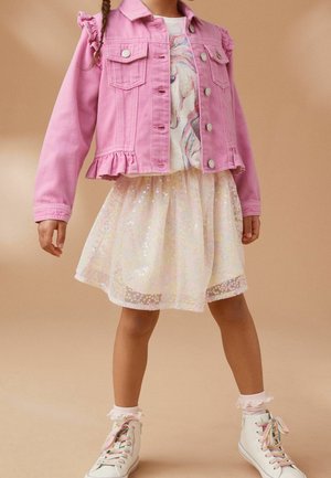 Fille portant une veste en jean rose, un t-shirt avec un imprimé licorne, une jupe crème scintillante, des baskets hautes blanches avec des lacets pastel, et des chaussettes à volants.