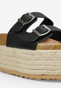 Sandales à plateforme noires avec deux brides réglables et boucles en argent, dotées d'une semelle en jute texturé et d'un coussin en liège.