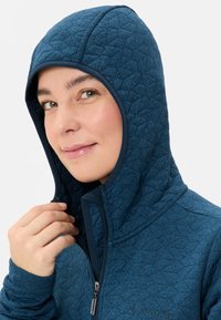 Blauwe gewatteerde hoodie met een aansluitende capuchon, textuurstof en rits aan de voorkant. Bevat een gelaagde kraag en subtiele logodetails.