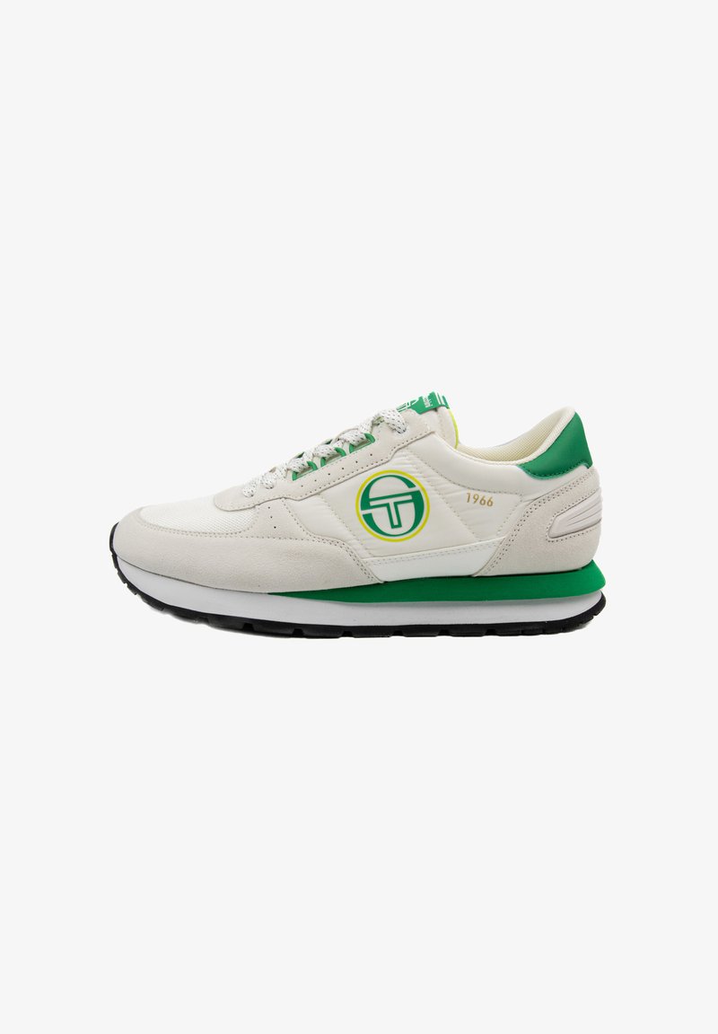 White suede sneakers with green accents, featuring a round logo, textured laces, and a layered sole in black and green.