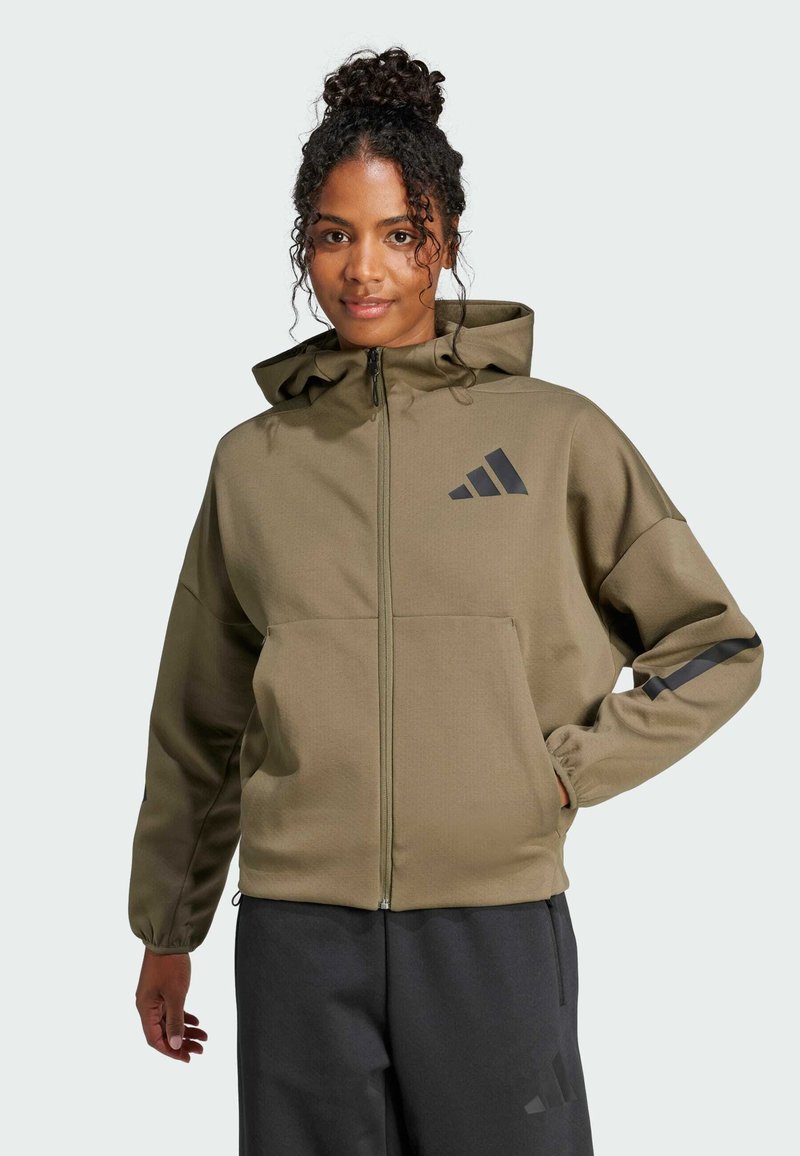 Olijfgroene ritsjack met capuchon en zwarte accenten en logo. Voorzien van elastische manchetten en voorzakken, gemaakt van glad, duurzaam materiaal.