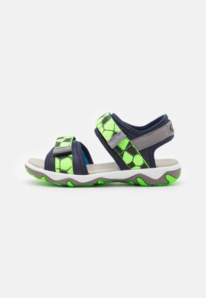 Sportsandalen mit navyblauen und neon grünen geometrischen Mustern, verstellbaren Klettverschlüssen und einer strukturierten weißen Laufsohle.