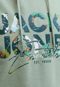 Lysgrøn hættejakke med multicolor splatter tryk "JACK & JONES essentials" og "EST. 1990" med synlige snore.