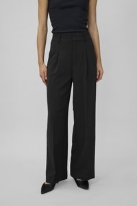 Black high-waisted wide-leg trousers made from a smooth fabric, featuring front pleats and belt loops, paired with pointed black shoes.