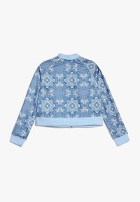 Sudadera corta azul con intrincados patrones blancos, puños y cuello acanalados, y un diseño de tejido texturizado.