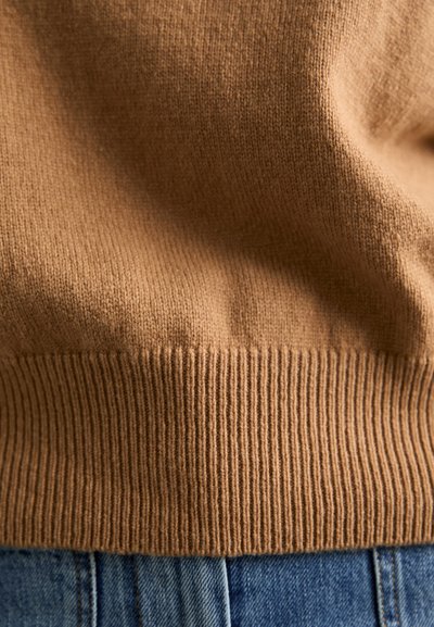 Barna kötött pulóver anyag bordás szegéllyel. Puha tapintású és sima felületű. Kék farmernadrághoz párosítva.