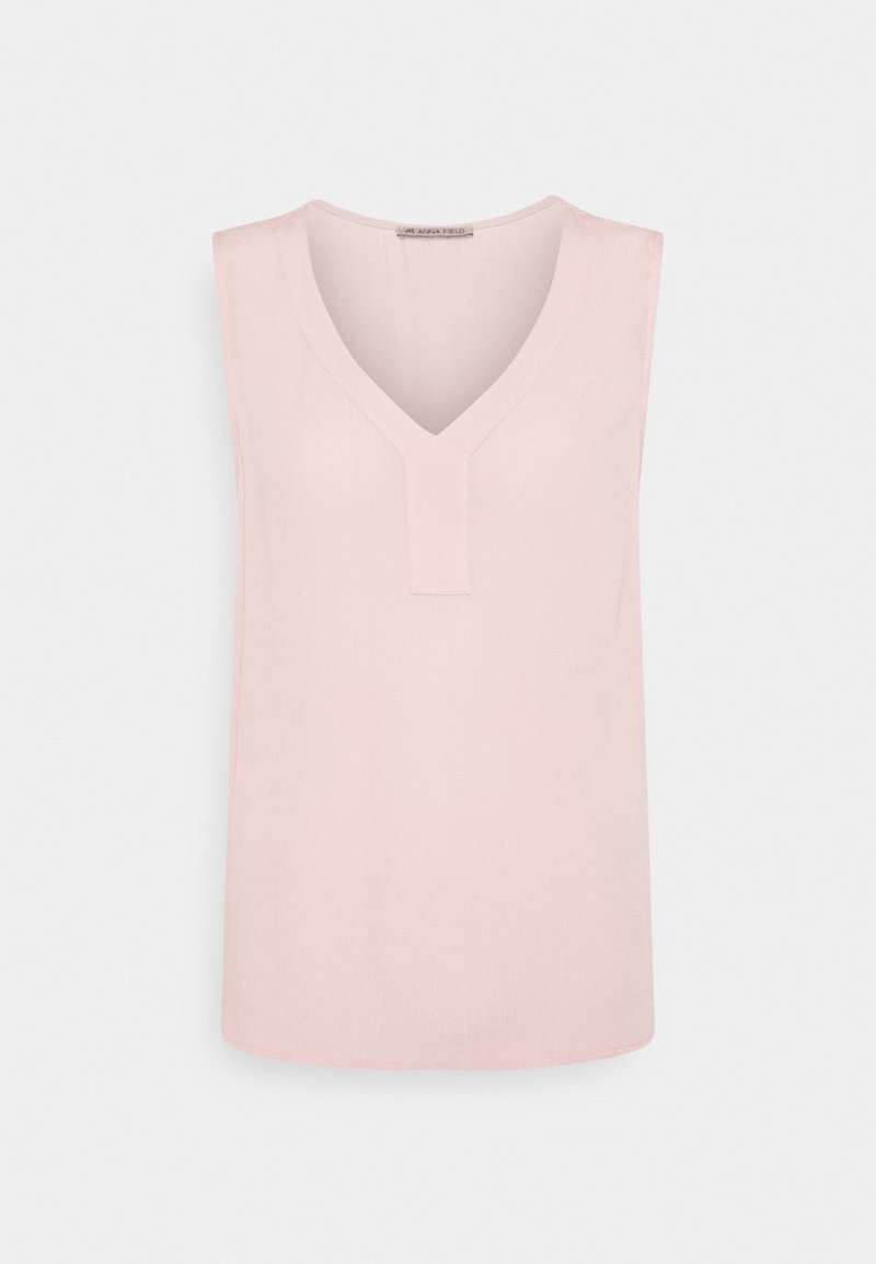Blouse sans manches rose pâle avec un décolleté en V et un petit détail vertical en tissu au centre devant.