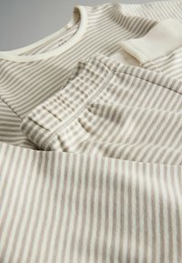 Hellbeige Outfit bestehend aus einem Rundhalsausschnitt-Oberteil und Hose mit elastischem Bund, beide mit dünnen horizontalen Streifen und weichem Material.